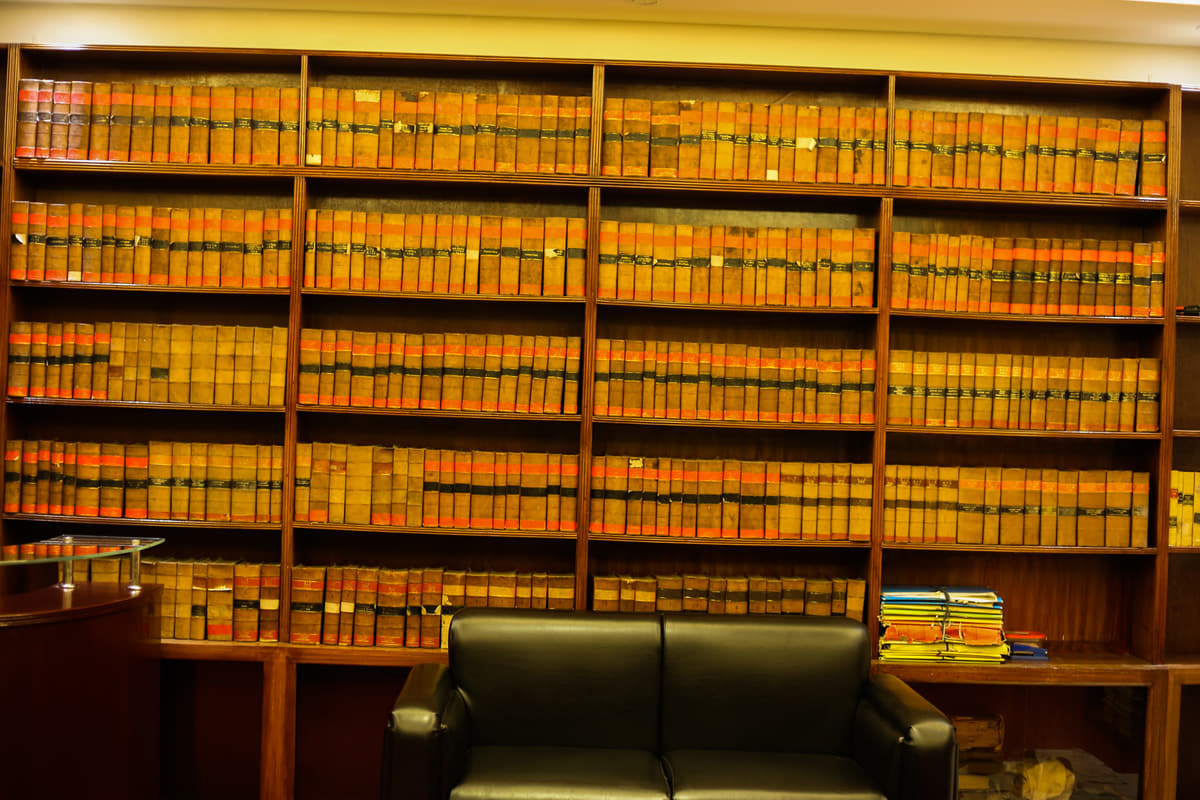 The reading end of the library, the bound reports rising above a settee and the reception desk.