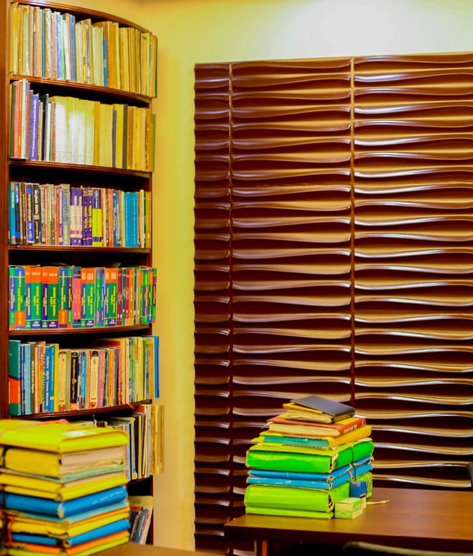 A corner of the consulting room: a bookcase of reports beside tied bundles of case files stacked on the desk.